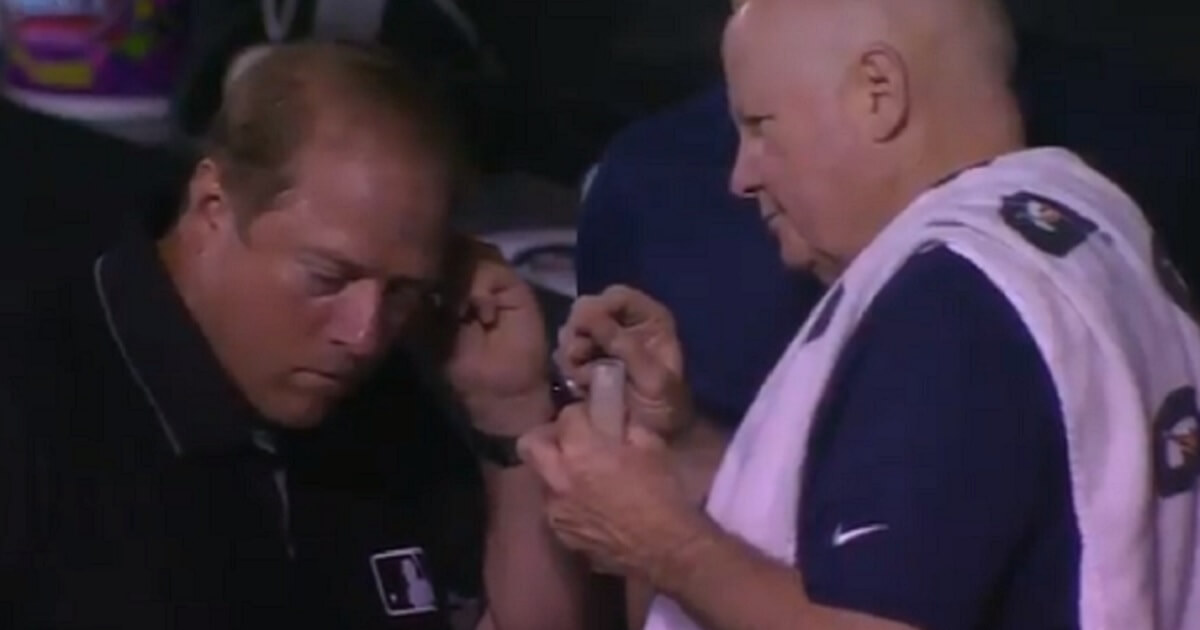 Umpire leans over as trainer hold tweezers
