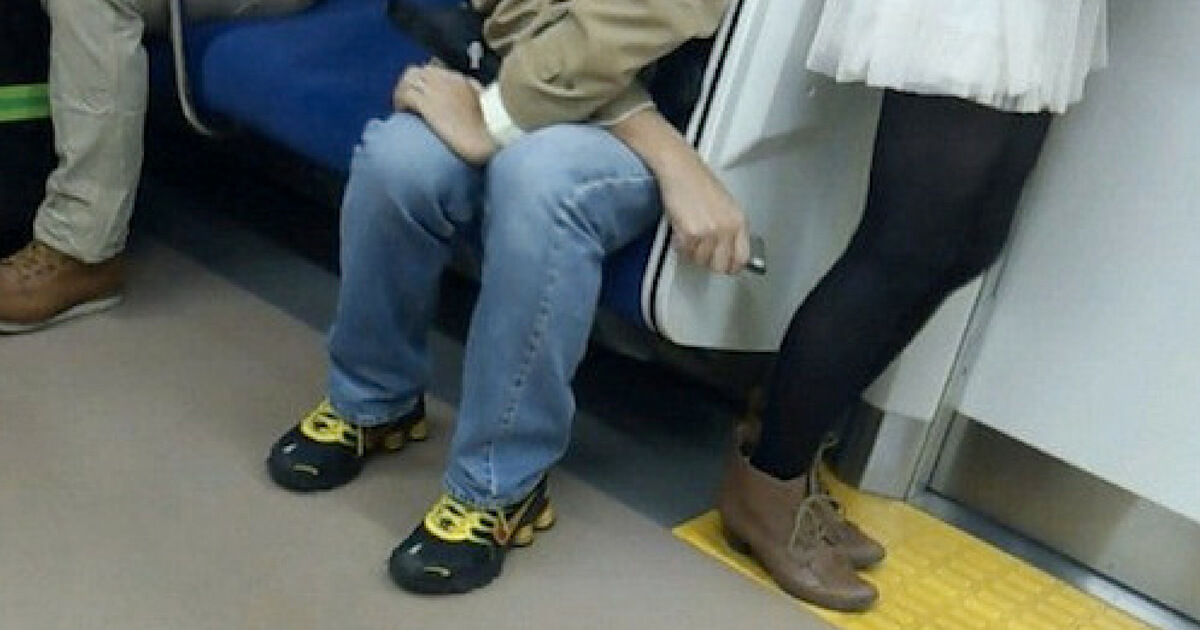 A man uses his phone to take an upskirt photo on a train.