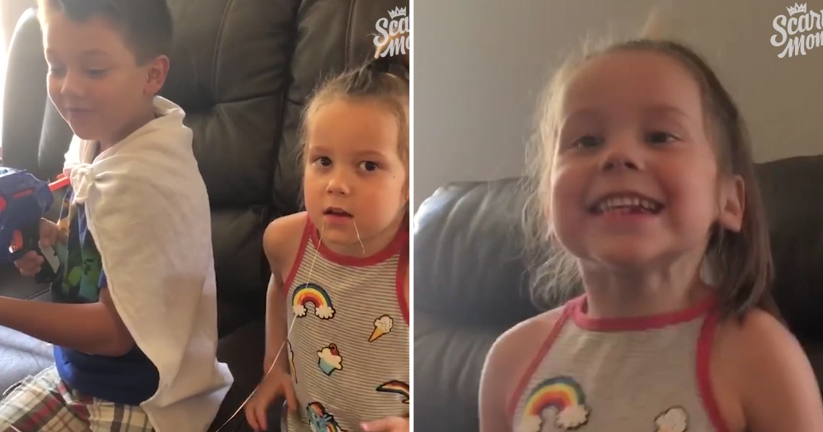 Little girl sits next to her brother with a nerf gun and then smiles big.