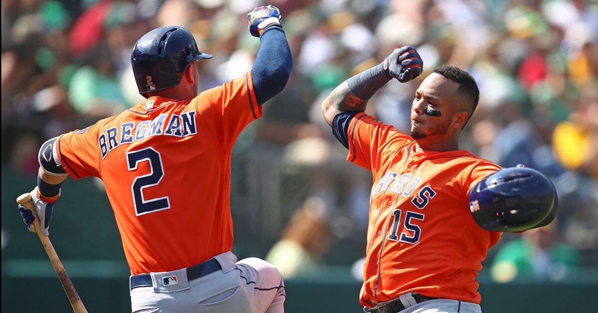 Two players raise their fists in celebration at home plate.