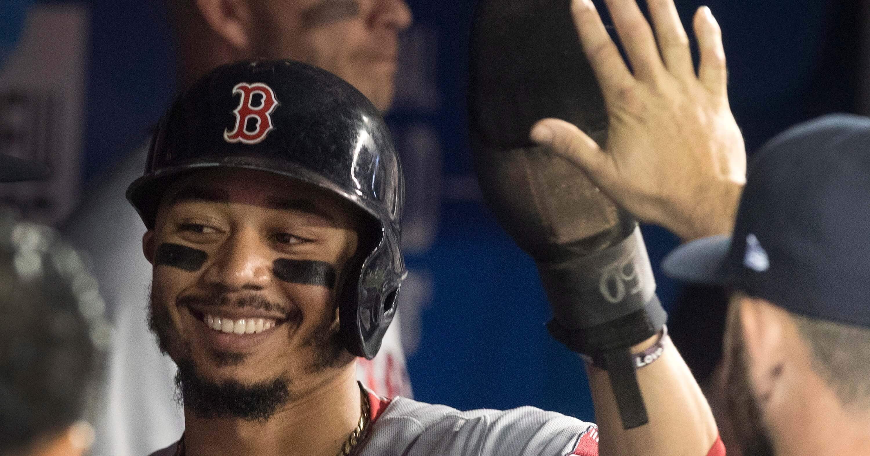 Boston Red Sox's Mookie Betts is congratulated in the dugout after scoring against the Toronto Blue Jays during the first inning of a baseball game Thursday, Aug. 9, 2018, in Toronto.