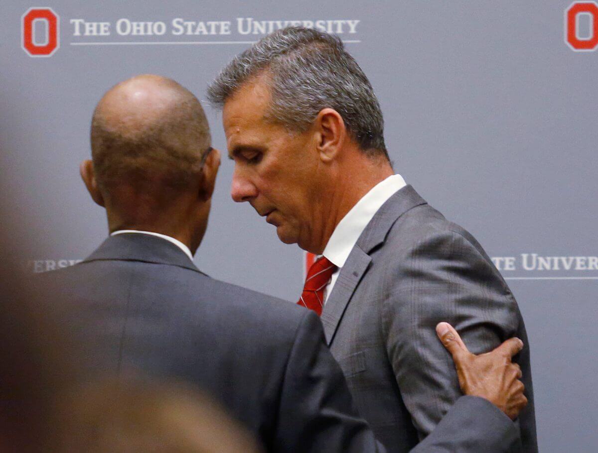 Ohio State University President Michael Drake offers words to football coach Urban Meyer, who leaves the stage following a news conference in Columbus, Ohio, Wednesday.