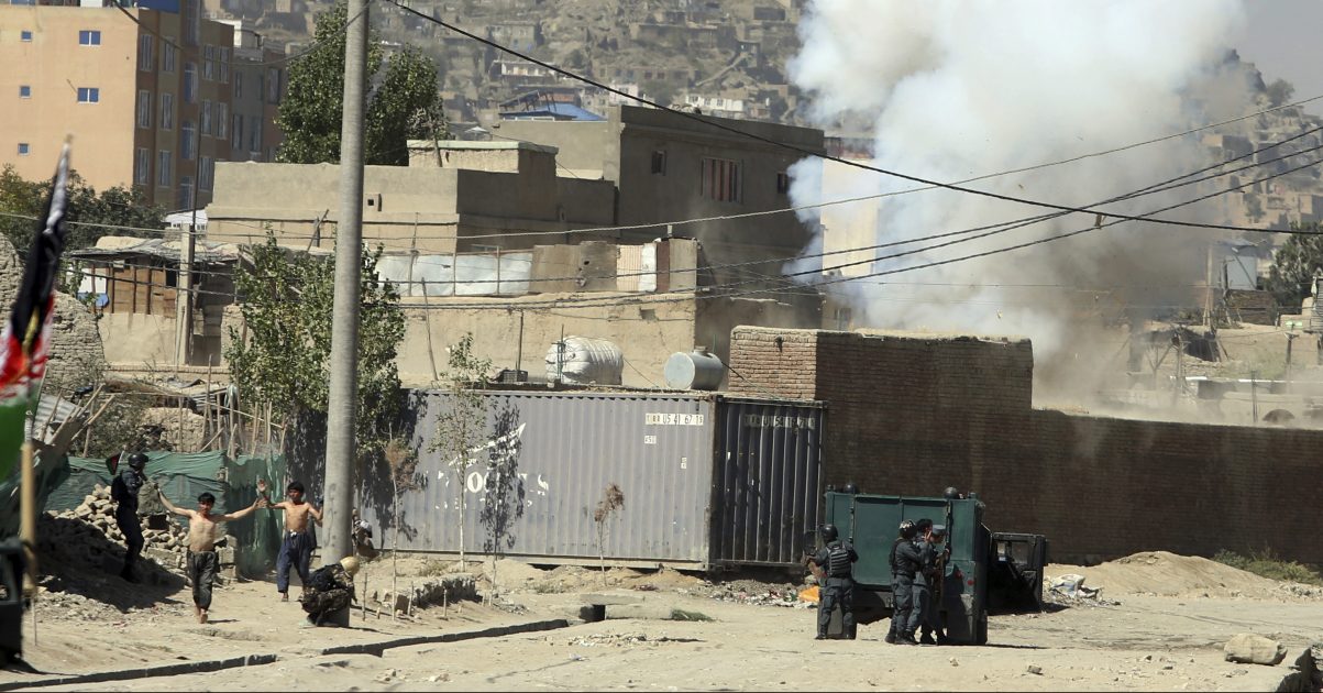 Smoke rises from a house where suspected attackers were hiding while policemen arrest two suspects, left, in Kabul, Afghanistan, Tuesday. The Taliban fired rockets toward the presidential palace in Kabul Tuesday as President Ashraf Ghani was giving his holiday message for the Muslim celebrations of Eid al-Adha. (AP Photo/Rahmat Gul)