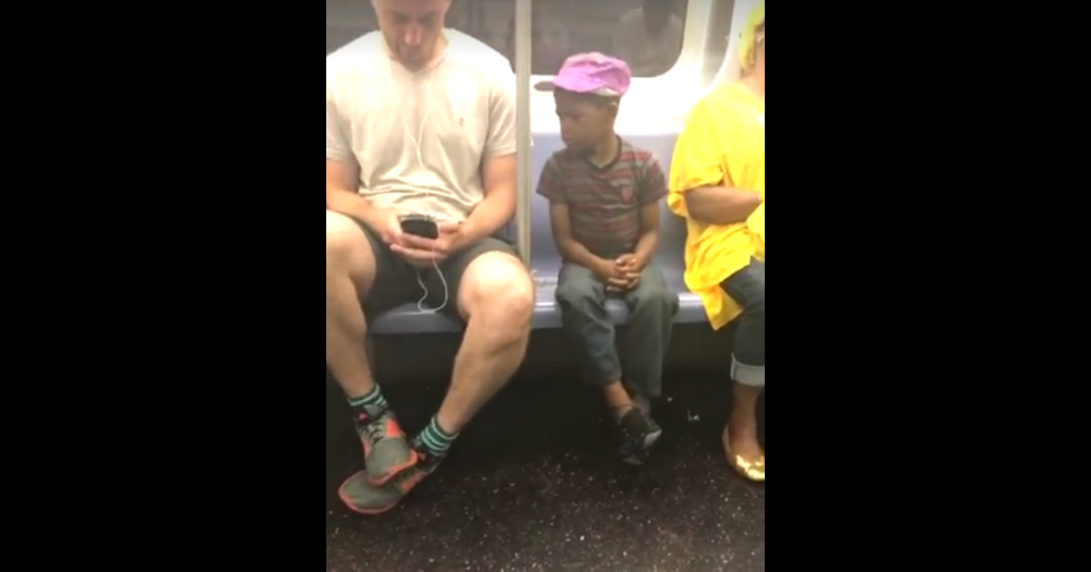 A woman in a New York City subway decided to start filming a little boy peeking over a man's shoulder, and she captured gold.