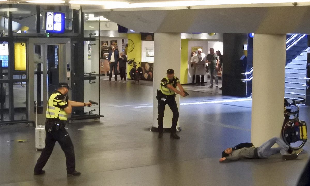 Dutch police officers point their guns at a wounded 19-year-old man who was shot by police after stabbing two people in the central railway station in Amsterdam, the Netherlands Friday Aug. 31, 2018.