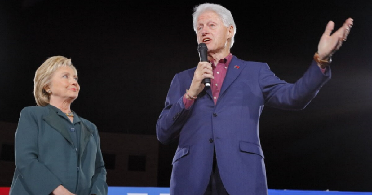 Hillary Clinton, left, standing with Bill Clinton, who holds a microphone.