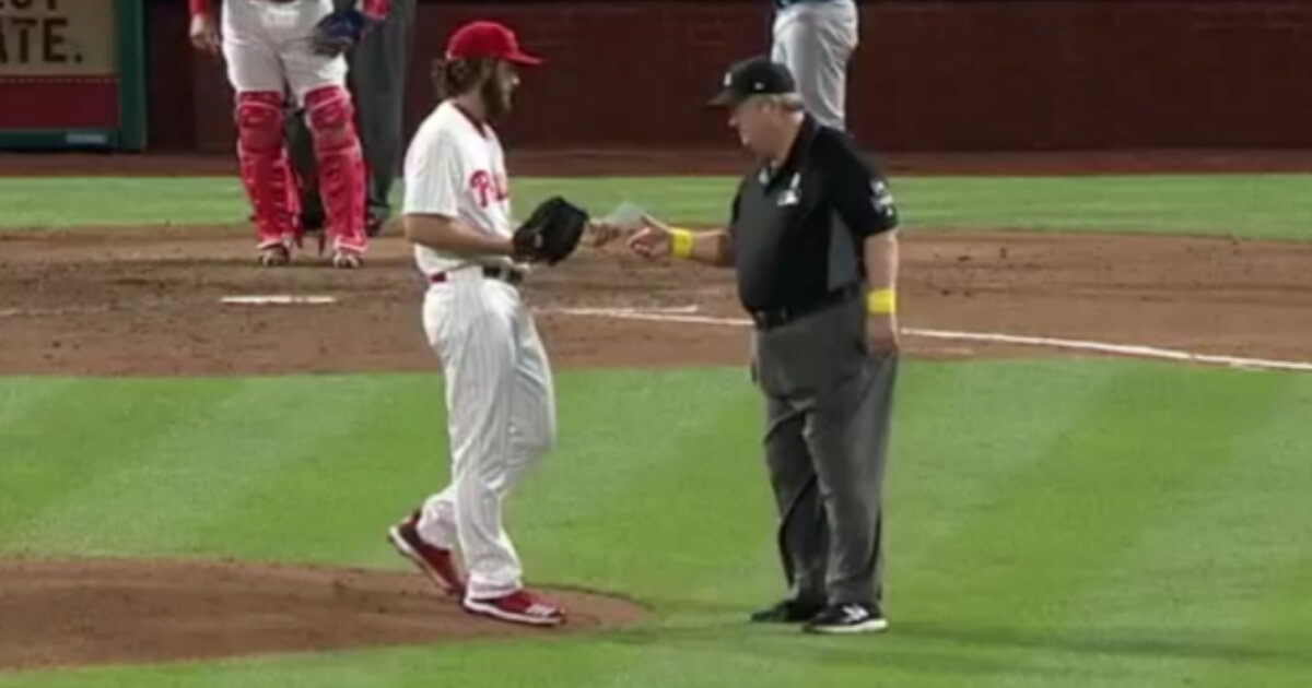 Phillies pitcher Austin Davis, left, hands over a cheat sheet with information about opposing hitters to umpire Joe West during Saturday's game at Philadelphia
