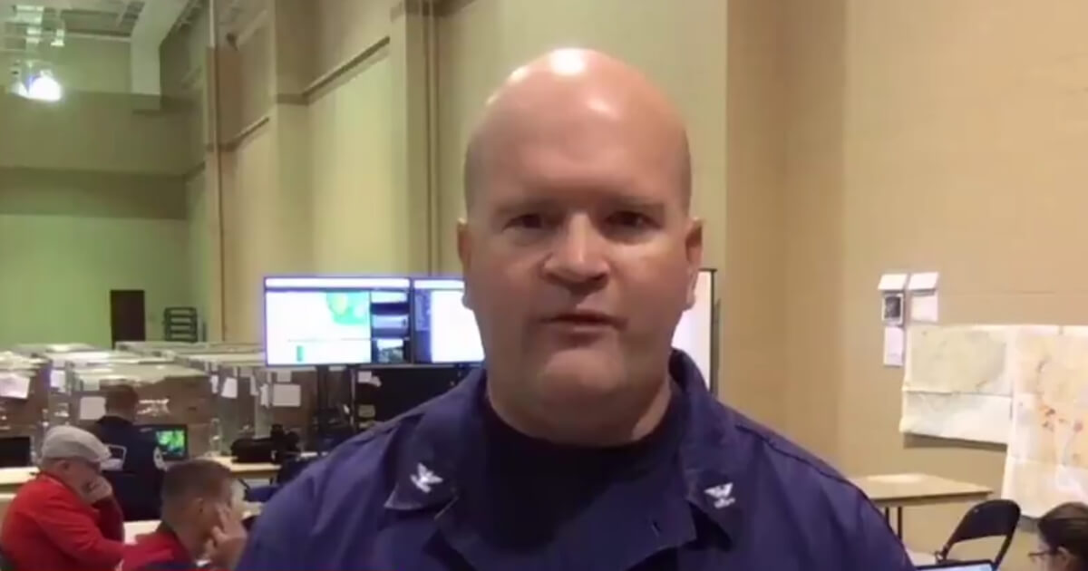 While a Coast Guard captain was talking about response efforts to Tropical Storm Florence in an interview on MSNBC, an unidentified employee in the background brought his thumb and pointer finger together while he brushed his hand along the side of his face.