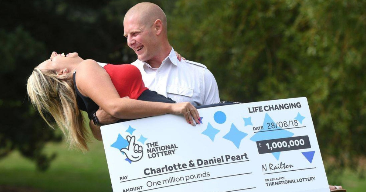 A husband carries his wife as she carries their giant lottery check.