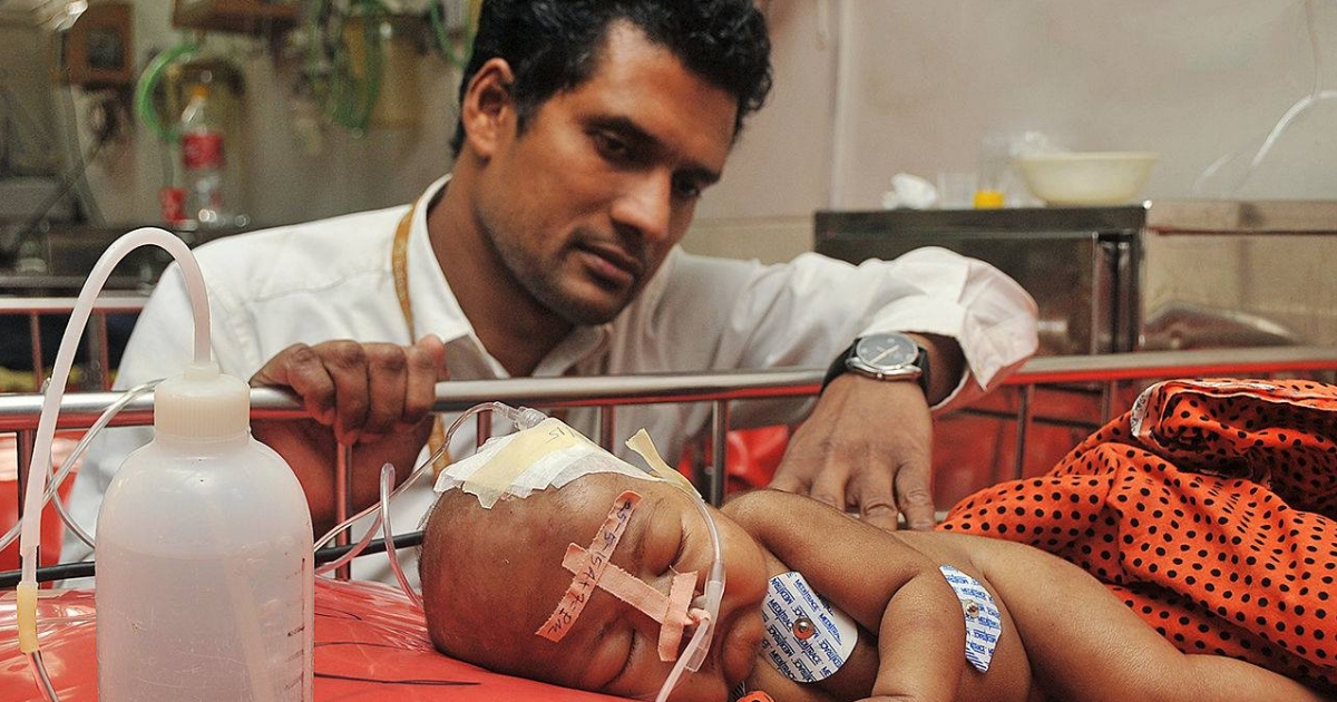 A doctor looking at a little baby with a tube coming out of his nose.