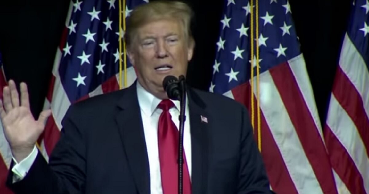 Trump speaks with American flags in the background