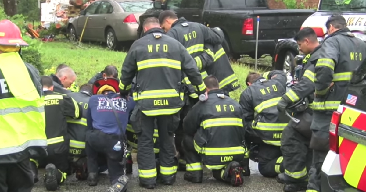 Firefighters praying outside the home of mother and baby who were killed in the storm.