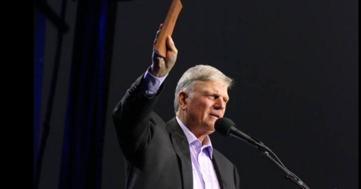 Rev. Franklin Graham is seen holding a Bible while preaching to a crowd.