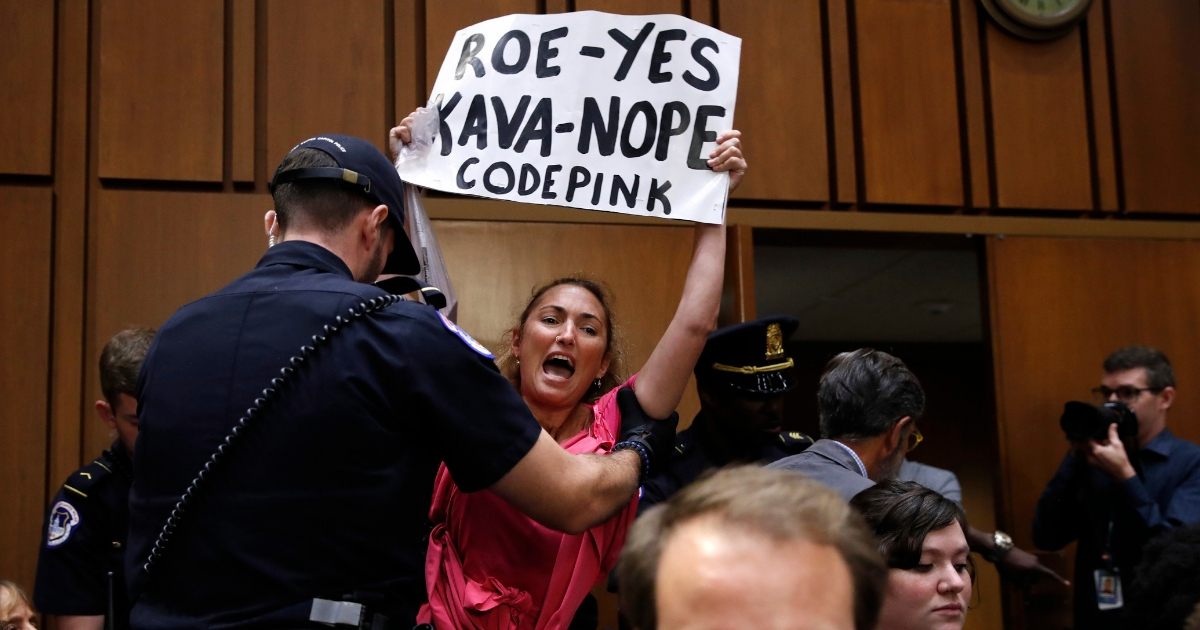 A woman stands and voices her opposition to Supreme Court nominee Brett Kavanaugh, during a Senate Judiciary Committee confirmation hearing Tuesday on his nomination for Supreme Court.