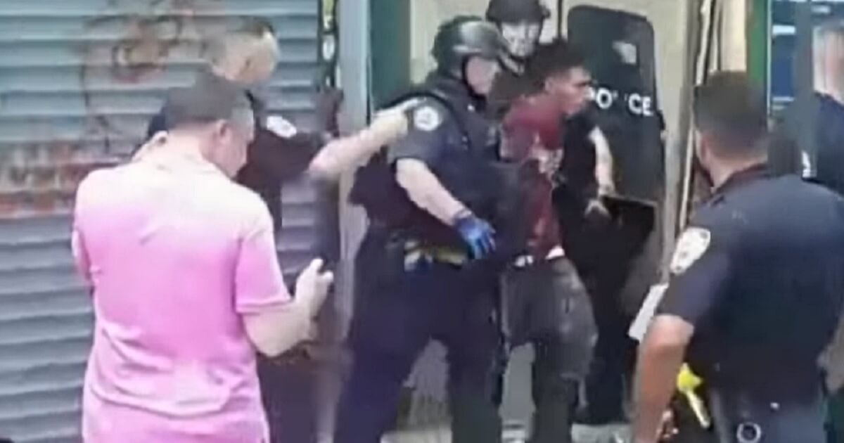 Arrested man surrounded by crowd of officers