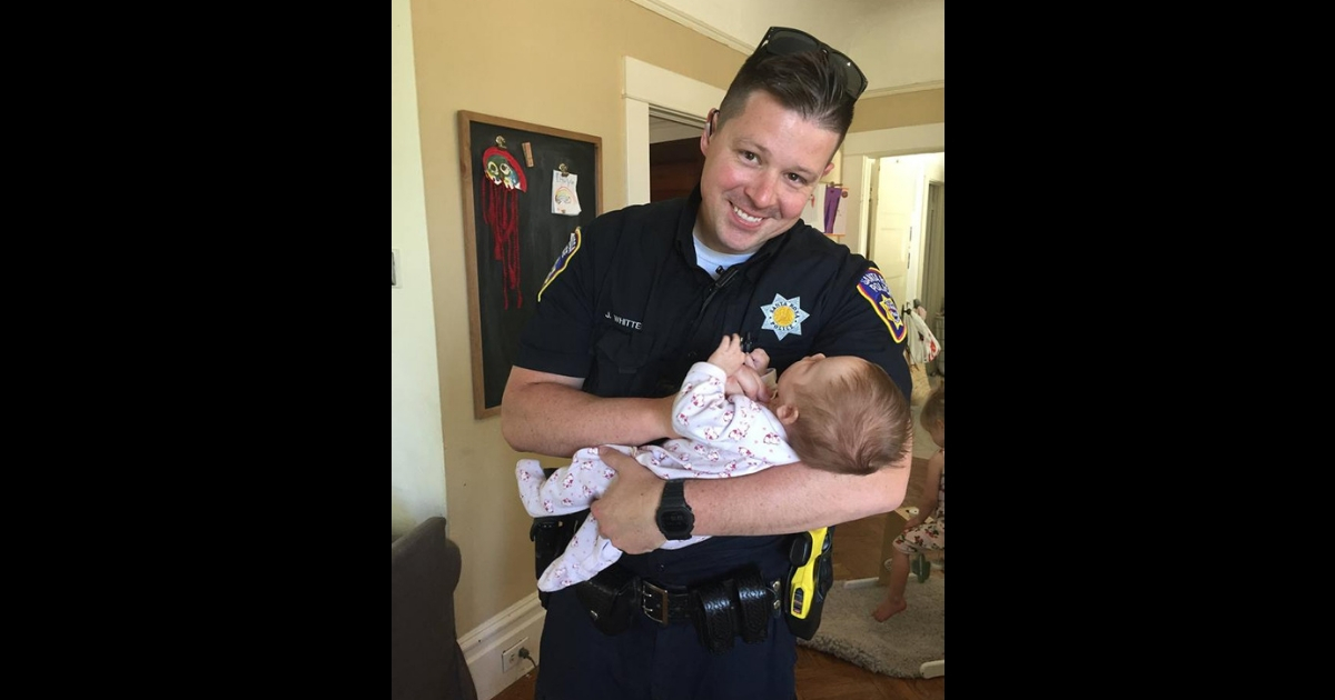 A police officer holds a little baby.