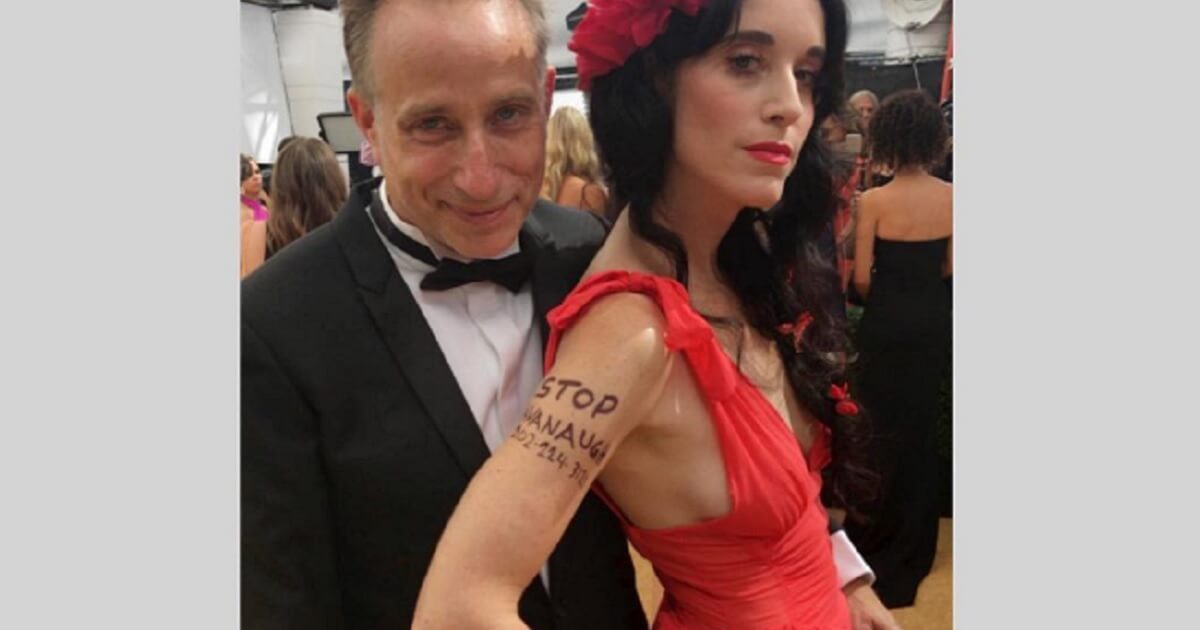 Sarah Sophie Flicker, wife of Emmy-nominated Netflix director Jesse Peretz, left, sports a "Stop Kavanaugh" message written on her skin for Monday night's Emmy Awards in Los Angeles.