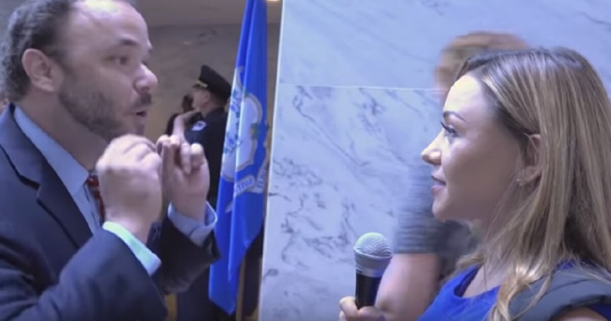 Woman holding microphone interviews obstinant Kavanaugh protester.