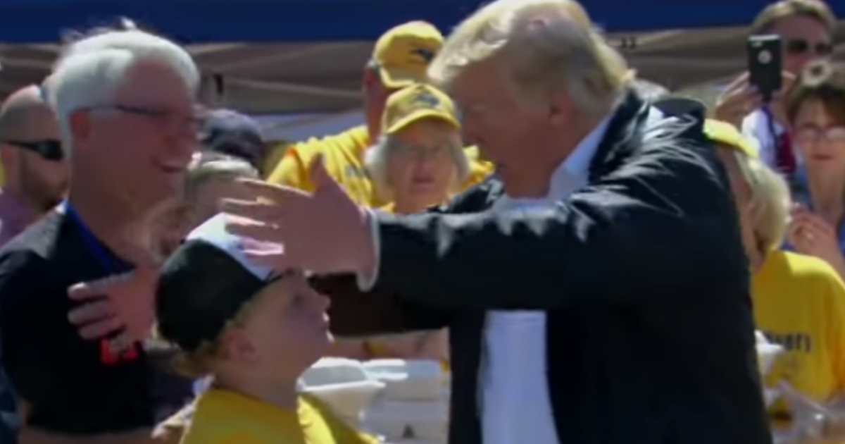 President Donald Trump embraces a young boy who had asked for a hug Wednesday during the president's visit to a site where volunteers were handing out meals to victims of Hurricane Florence.