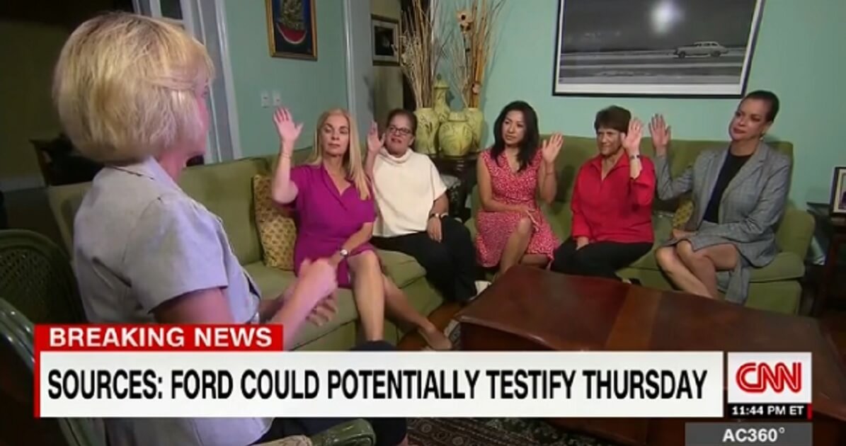 A group of women with their hands raises, indicating they support Brett Kavanaugh.
