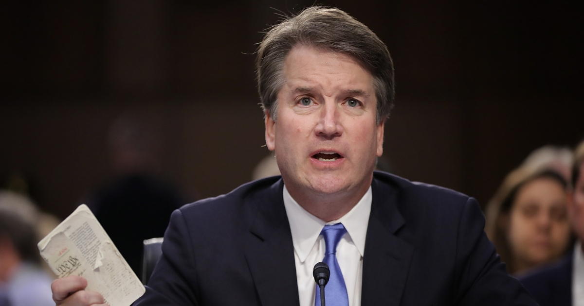 Supreme Court nominee Judge Brett Kavanaugh holds up a small copy of the U.S. Constitution while answering questions before the Senate Judiciary Committee during the second day of his Supreme Court confirmation hearing.