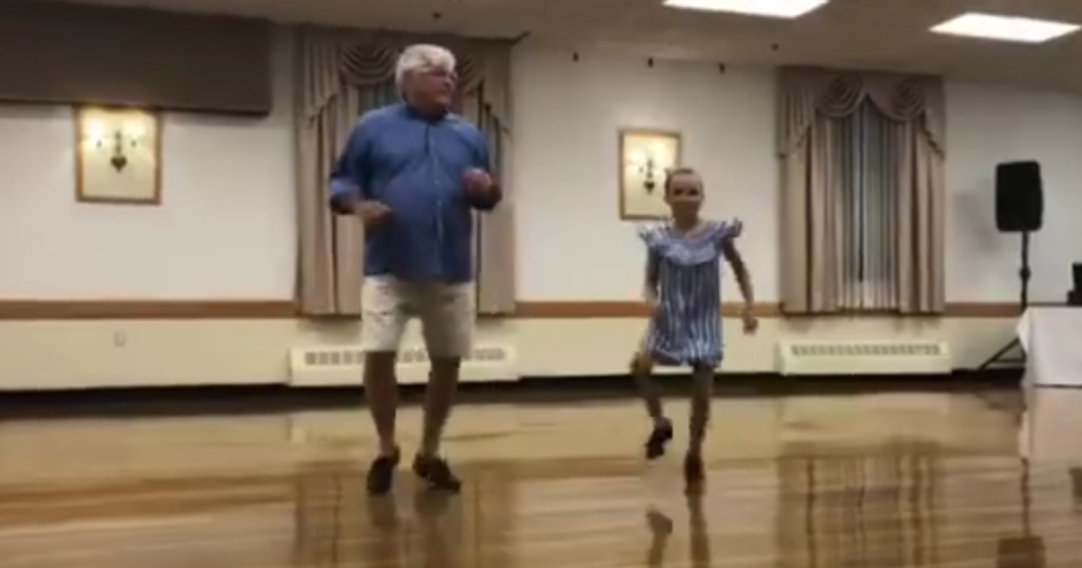 A grandfather dancing with his granddaughter.