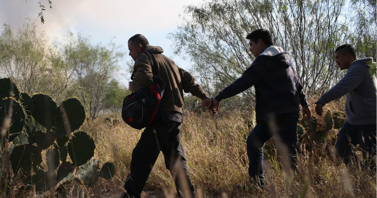 Immigrants walk handcuffed after illegally crossing the U.S.-Mexico border