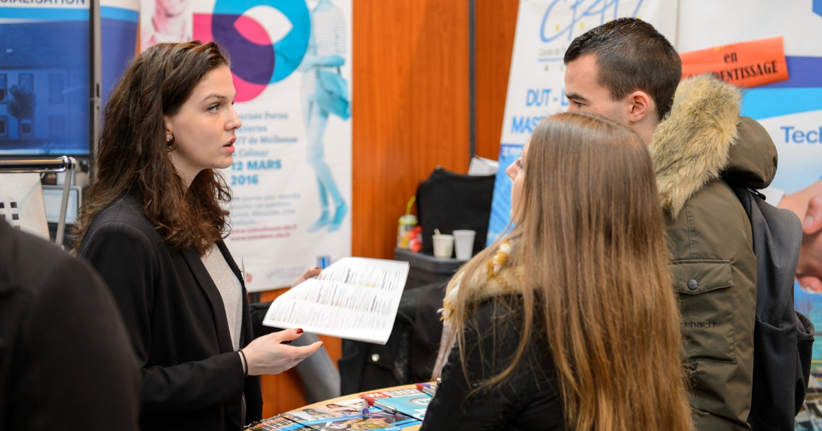 Women speaks to two people at a job fair.