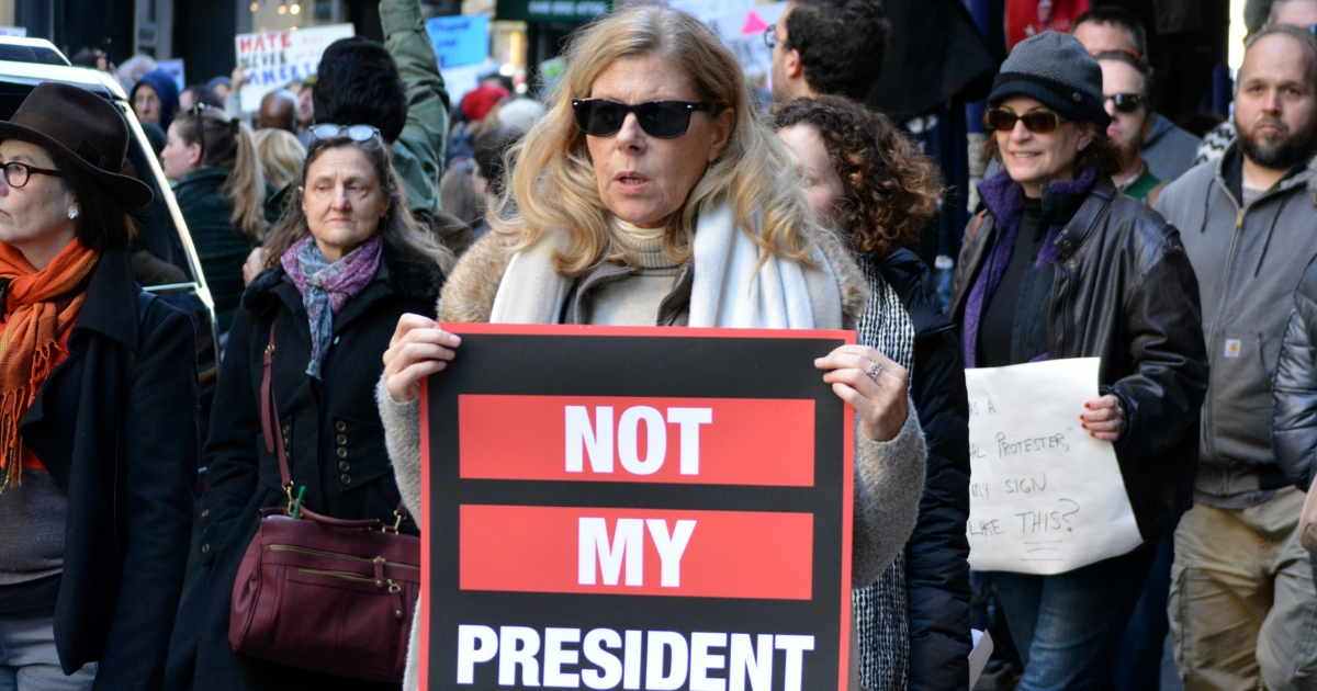 Woman carrying 'not my president' sign.