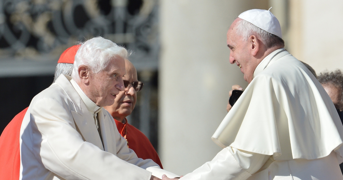 Pope emeritus Benedict XVI (L) speaks with Pope Francis during a papal mass