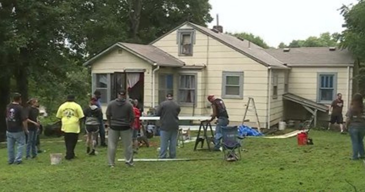 A group of people work on a woman's house.