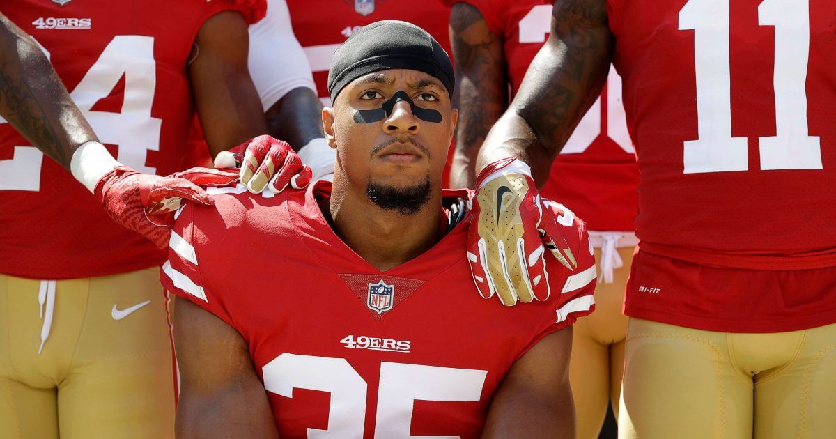 Then-San Francisco 49ers safety Eric Reid (35) kneels in front of teammates during the playing of the national anthem before a 2017 game against the Carolina Panthers.