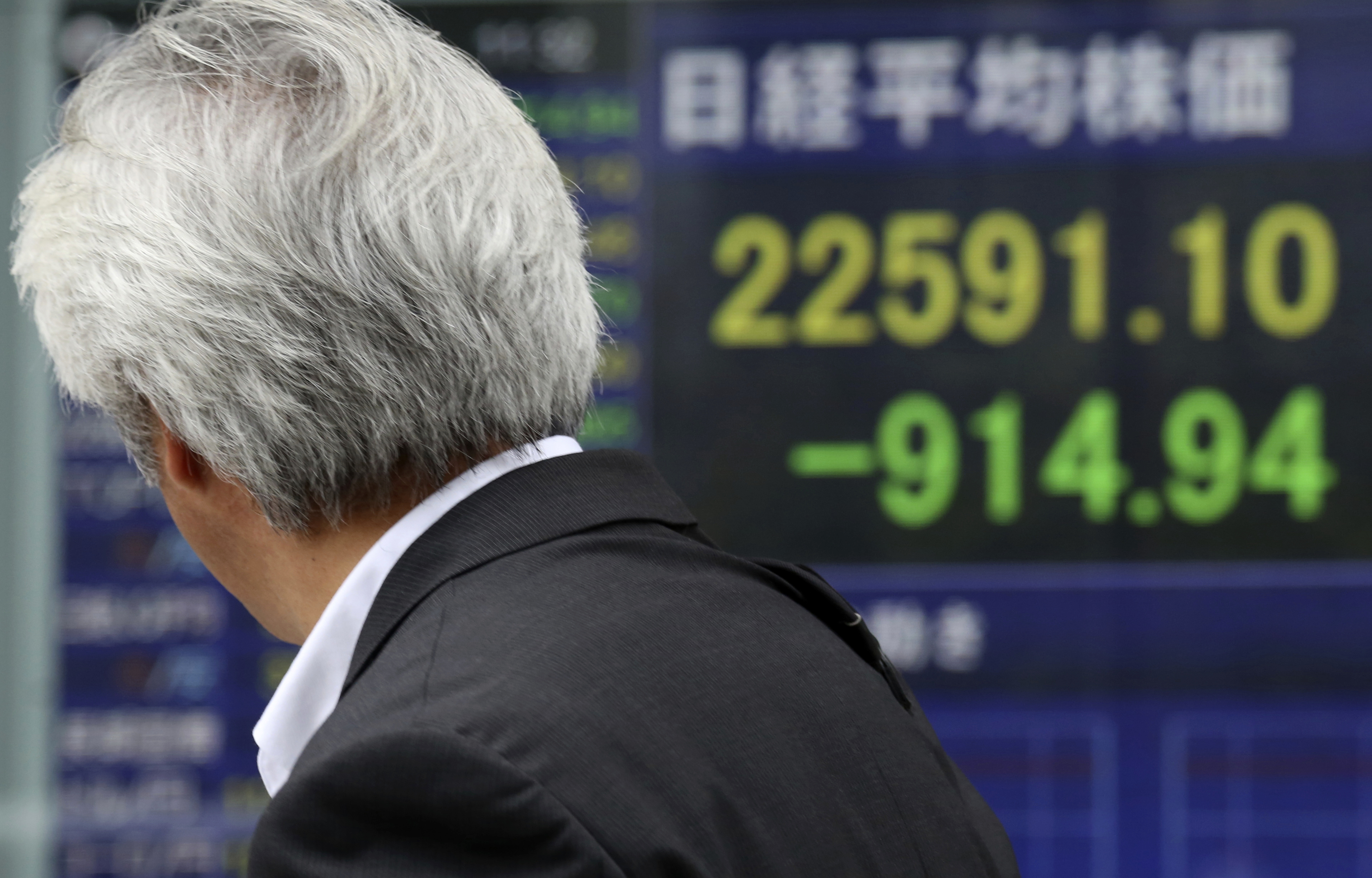 A man looks at an electronic stock board of a securities firm in Tokyo on Thursday. Asian markets tumbled a day after Wall Street slumped on a heavy selling of technology and internet stocks. Japan’s benchmark fell by an unusually wide margin of 3.9 percent.