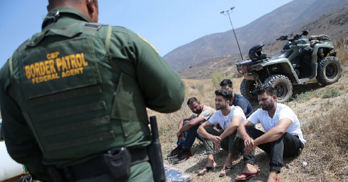A U.S. Border Patrol agent guards a group of men, originally from India, who were caught trying to enter the United States via the Mexican border in July.