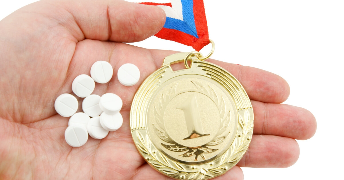 Pills are held next to a gold medal