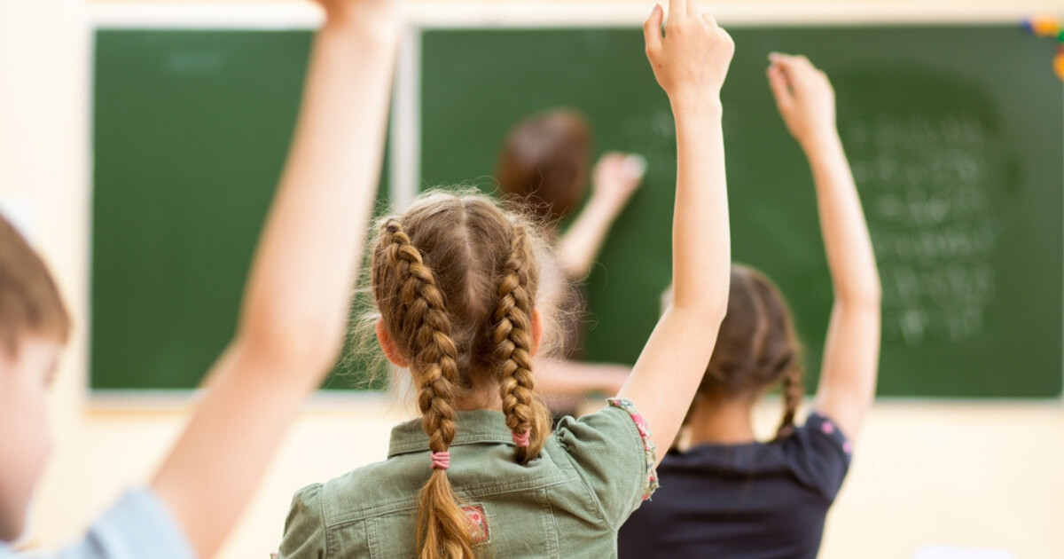 Children raise their hands in a school classroom