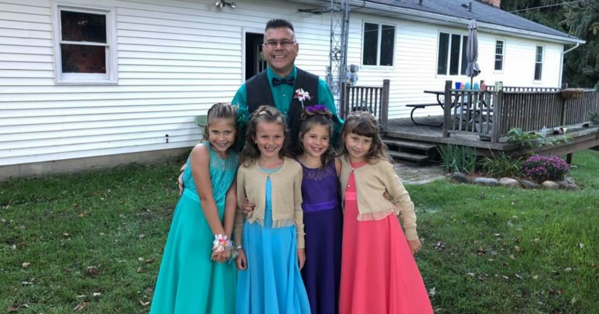 A teacher stands with his daughters and two other girls.
