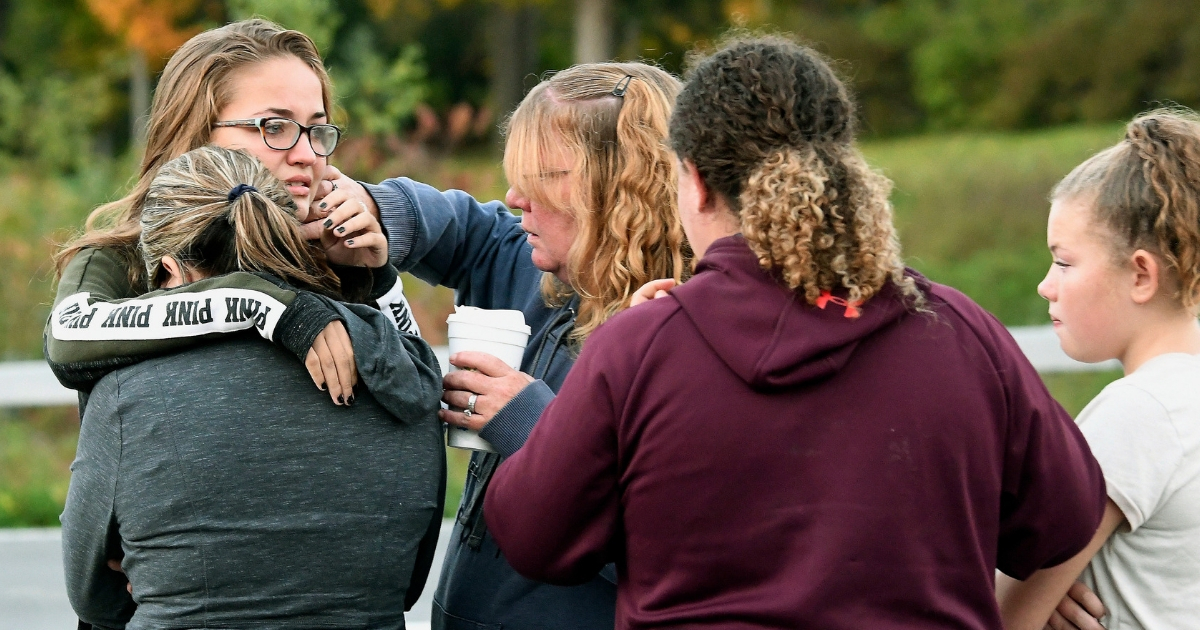 Friends of some of the 20 victims who died in Saturday's fatal limousine crash comfort each other Sunday after placing flowers at the intersection in Schoharie, New York.