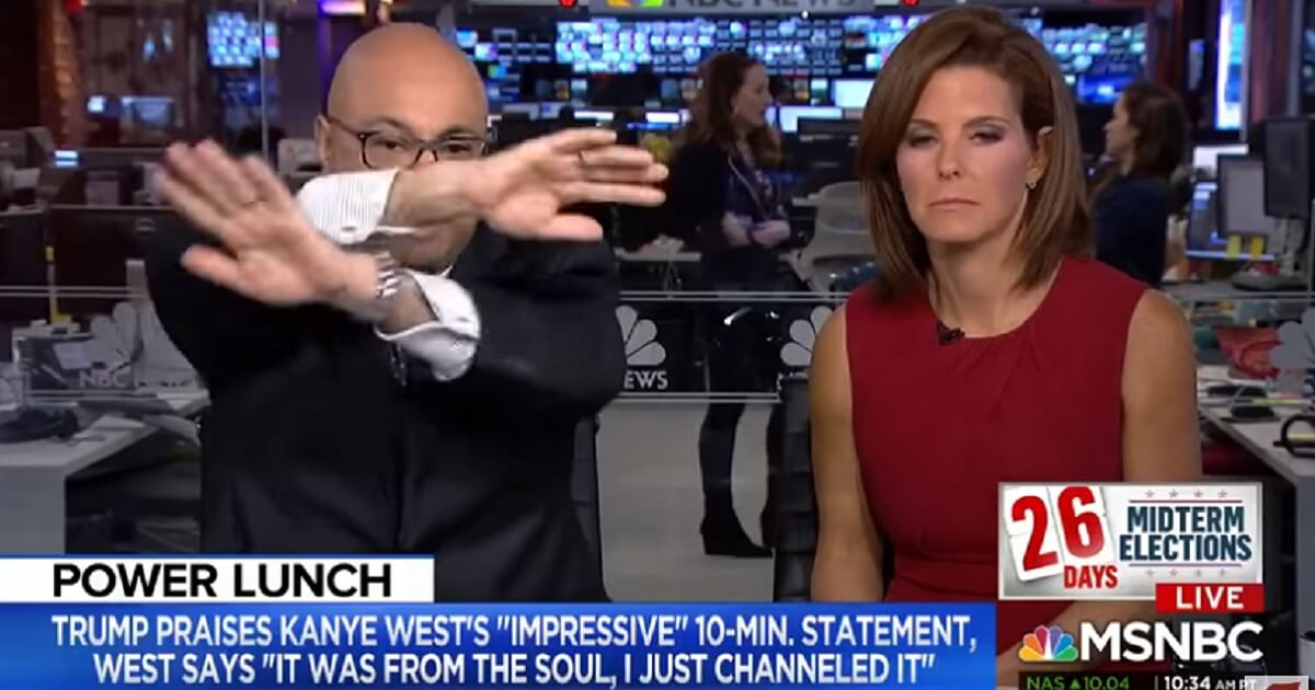 MSNBC host Ali Velshi waves his arms to signal viewers to turn up their volume again as he and co-host Stephanie Ruhle prepare to mock rapper Kanye West's visit to the White House on Thursday with football great James Brown.