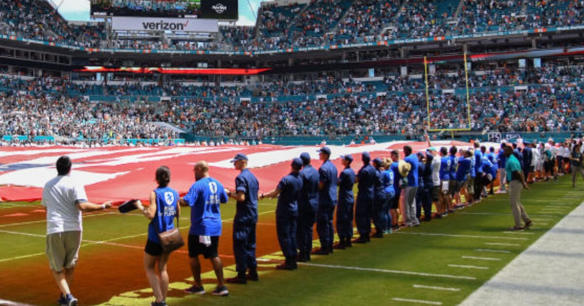 A large American flag is unfurled for the playing of the national anthem prior to a Miami Dolphins home game.