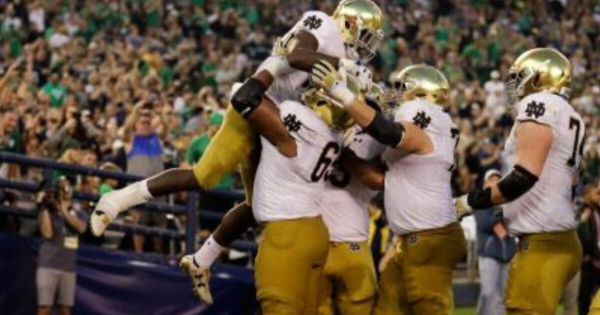 Notre Dame running back Dexter Williams is lifted by teammate long snapper Michael Vinson after scoring a touchdown during Saturday's game against Navy