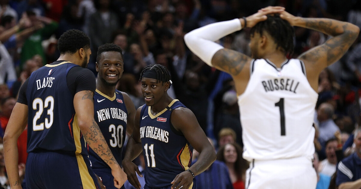 The Nets' D'Angelo Russell, right, watches while Jrue Holiday (11), Anthony Davis (23) and Julius Randle (30) of the Pelicans celebrate their improbably comeback victory Friday at the Smoothie King Center in New Orleans.