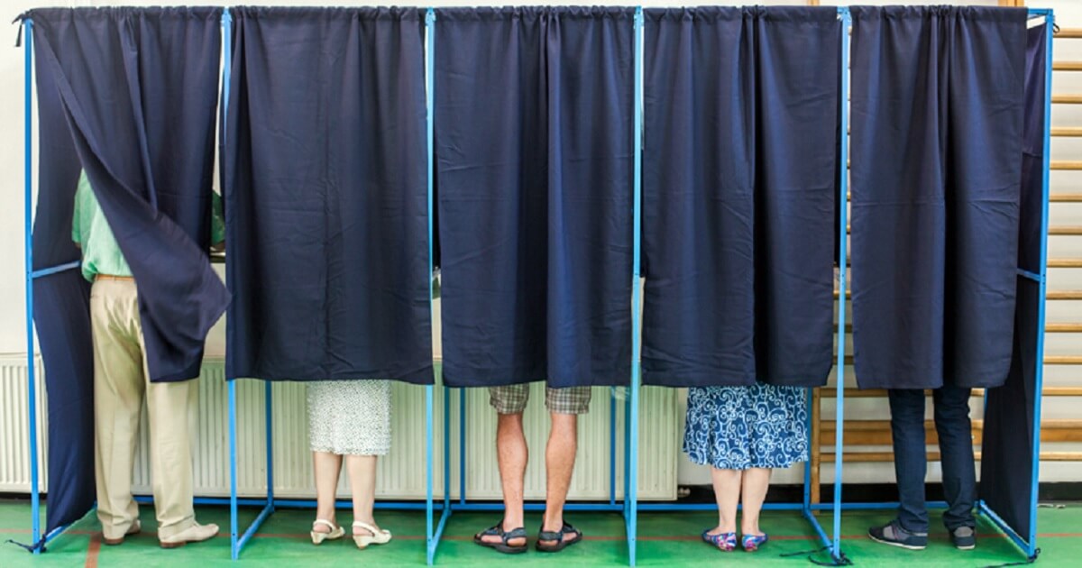 Exterior shot of voters inside polling places with curtains pulled.