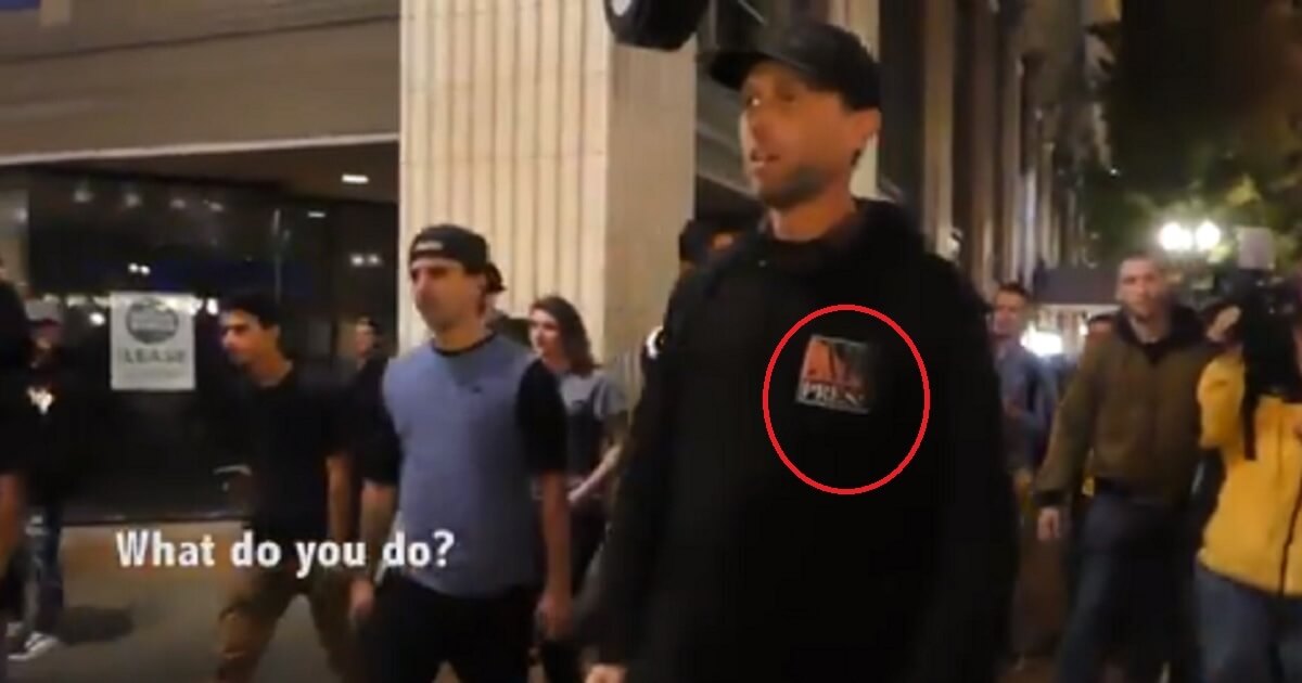 Man standing in crowd with "AK Press" on his hoodie.