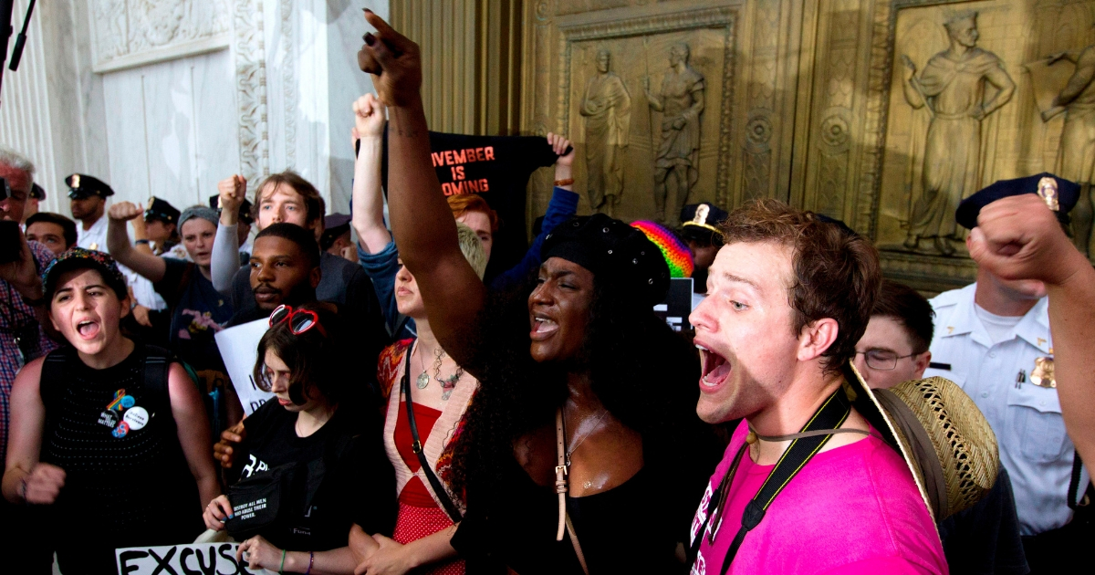 Demonstrators block the main entrance door as they take the steps of the U.S. Supreme Court on Saturday to protest the confirmation of Brett Kavanaugh.