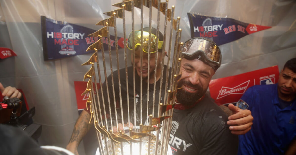 Catcher Sandy Leon of the Boston Red Sox celebrates with the World Series trophy