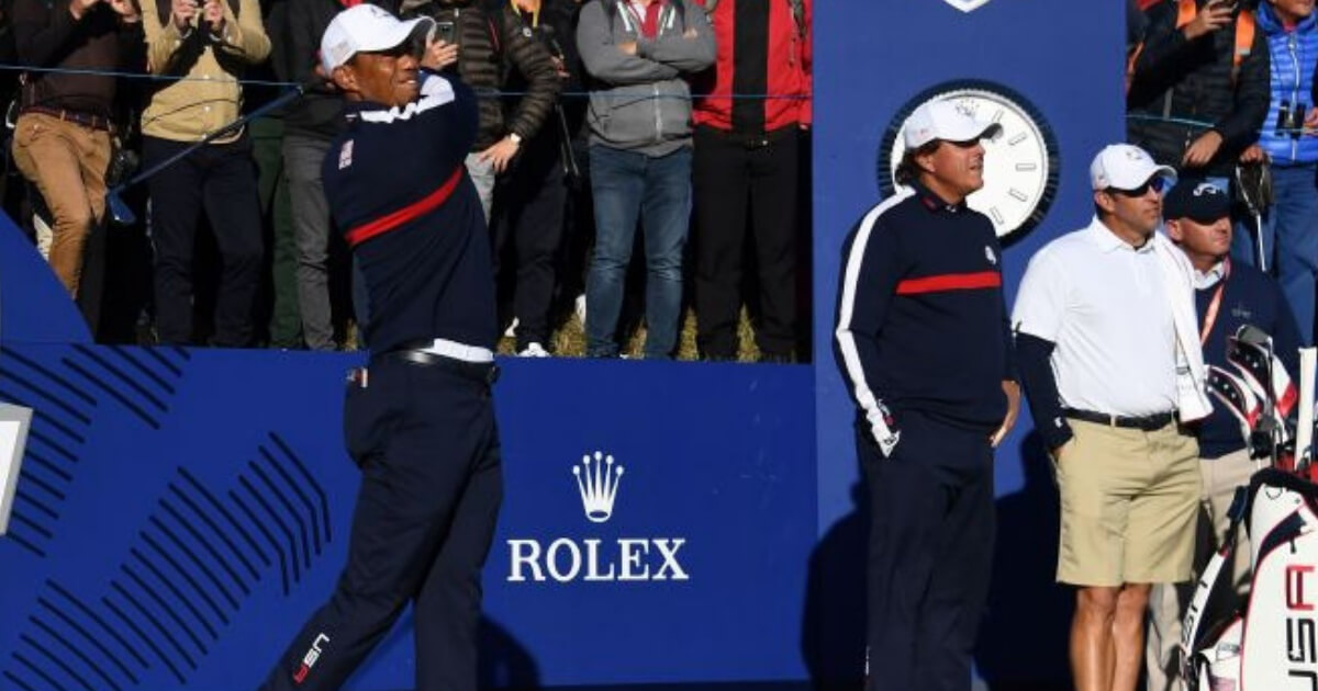 Tiger Woods, left, tees off as teammate Phil Mickelson looks on during a practice session ahead of the 42nd Ryder Cup