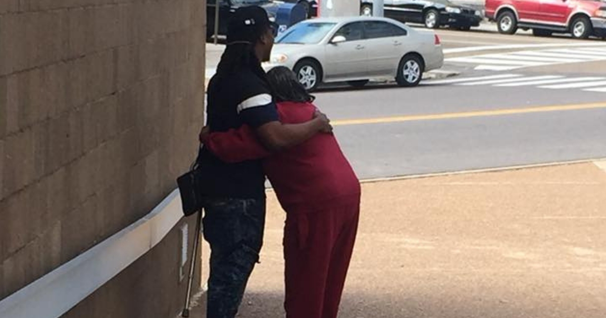 A woman in pink hugs a stranger who helped her cross the street.