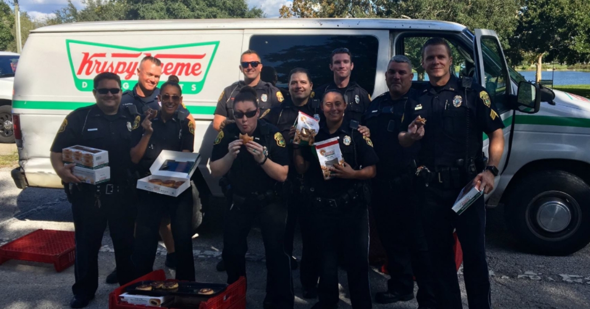 Cops pose in front of Krispy Kreme van.