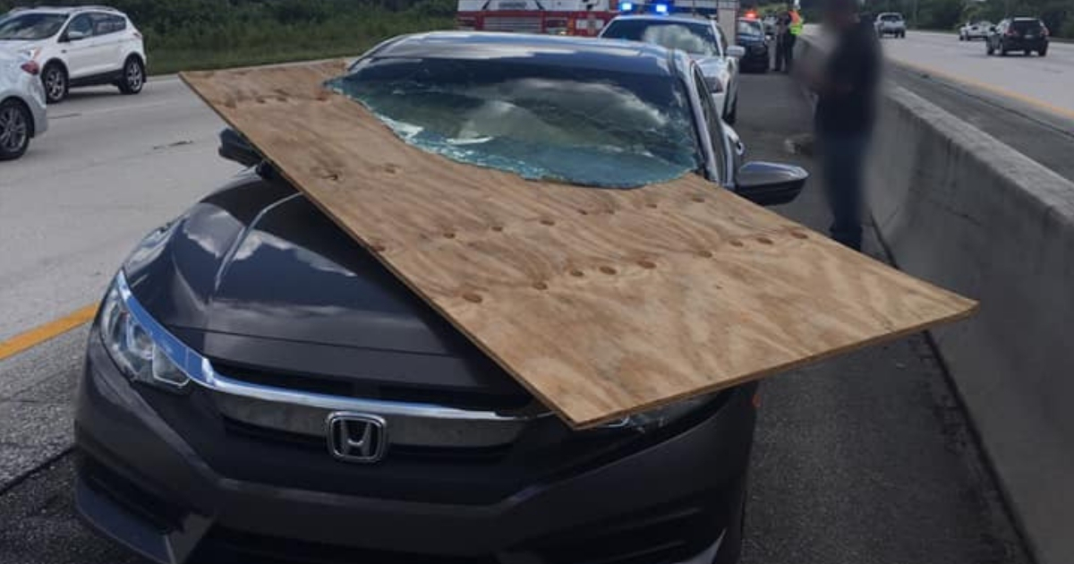 A piece of plywood sticking out of a car windshield.